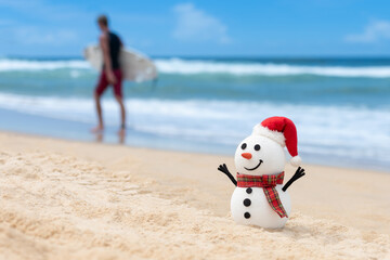 When snowmen need a break too. Beach day for a snowman. Surfer walking with surfboard in the background