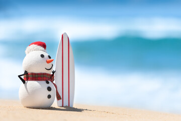 A Snowman is watching the waves, standing on beautiful beach with a surf board.