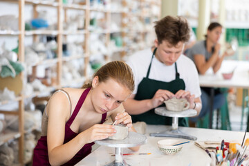 Students teenage girl and teenage boy sculpt ceramic product from raw clay in workshop