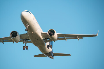Close-up of a passenger airplane approaching the airport, preparing to land. Blue background. Clear sky.