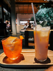 Two refreshing cocktails served on a wooden tray in a cozy indoor setting