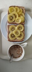 Desayuno o merienda saludable con leche, cereales solubles y rebanadas de pan de molde y rodajas de kiwi amarillo