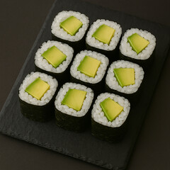 Nine pieces of avocado sushi on slate