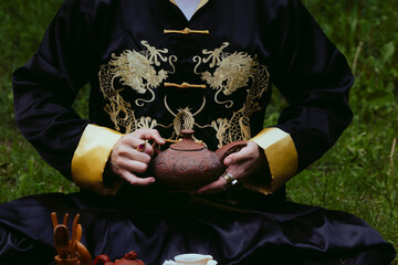 Man wearing a black kimono holding a tea pot for traditional Chinese tea ceremony
