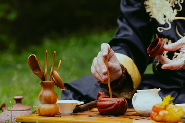 Traditional Chinese tea ceremony outdoors. Man preparing a beverage. Copyspace for text