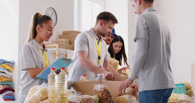 Team of volunteers work together to assemble food kits into boxes. Group collective effort embodies the essence of teamwork, charity, and donation support, making a impact through help.