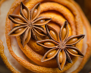 Two star anise pods resting on a spiral of dried orange peel captured in vibrant macro detail
