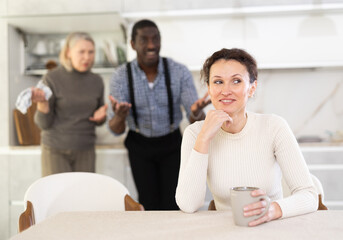 Upset woman not talking after disagreement with husband and mother standing behind
