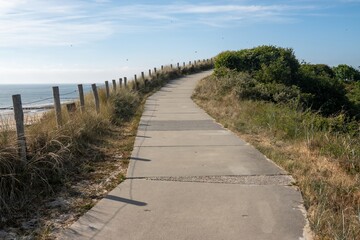 Fototapeta premium Winding paved path along coastal dunes leading to the sea