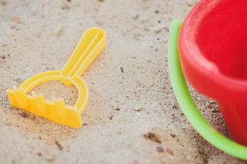 Colorful plastic rake and bucket on sand at playground
