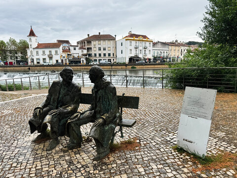Statue of two people Fernando Lopes-Gra&ccedil;a and Fernando Ara&uacute;jo Ferreira talking by the Nab&atilde;o river in Tomar, Portugal