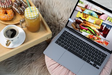Laptop with food blog web site, coffee, juice and donuts on floor indoors, above view