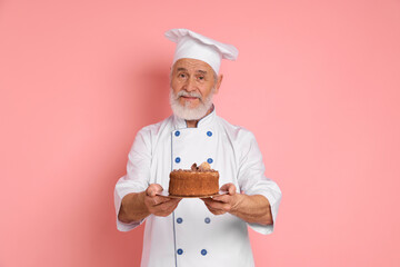 Professional pastry chef with delicious chocolate cake on pink background