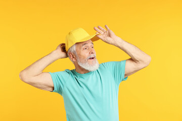 Elderly man in stylish outfit on orange background