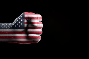 A clenched fist proudly displaying the American flag, set against a stark black background. The fist symbolizes strength, unity, and patriotism