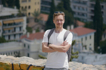 A man tourist with a backpack at the background of the panorama of the city of Athens at the...