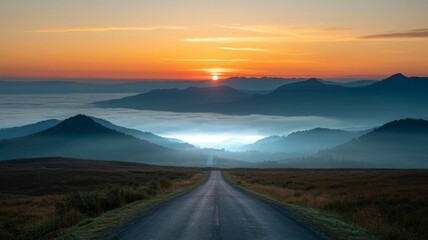 A serene sunrise over mountains, with a winding road leading into the misty valley below.