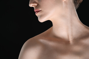 Woman with beautiful collarbones and neck on black background, closeup