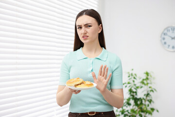 Gluten free diet. Young woman refusing pretzels indoors