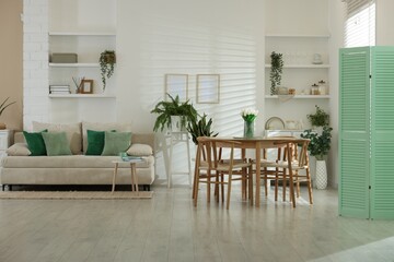 Comfortable sofa, table, chairs and green houseplants indoors. Interior design