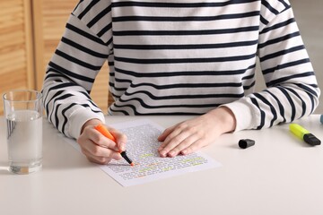 Woman highlighting important information at white desk indoors, closeup