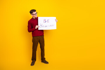 Young Man Holding Sign with Inspirational Message on Vibrant Yellow Background