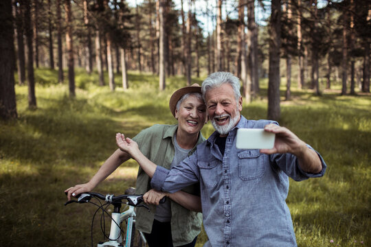 Senior couple taking a selfie during a nature bike ride in the forest