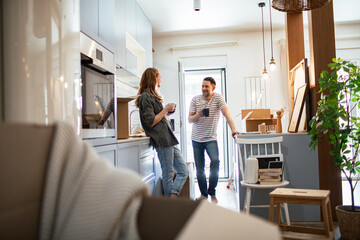 Happy couple unpacking boxes together in new kitchen