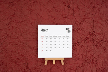 March 2026 calendar on red crumpled paper background. Directly above.