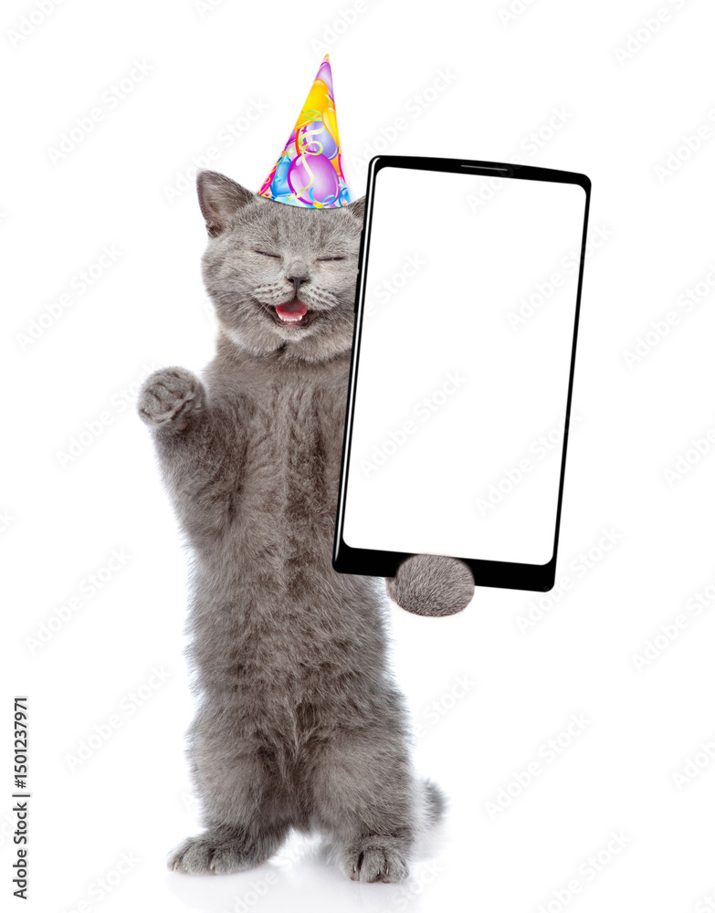 Aufkleber Laughing cat with open mouth wearing party cap standing on hind legs and showing big smartphone with blank screen. Empty space for text. isolated on white background