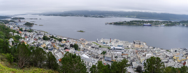 View of the port of Alesund on the west coast of Norway, with the island of Hessa in the background under a cloudy sky seen from Mount Aksla