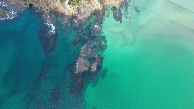 Drone captures the contrast of deep blue sea and exposed rocks near a coastal headland in Matapouri, New Zealand.