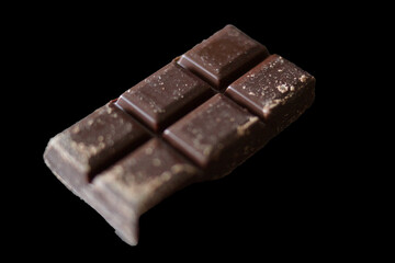 A sleek dark chocolate bar made up of six perfectly aligned squares. Each piece displays a smooth, glossy surface with subtle patterns. 