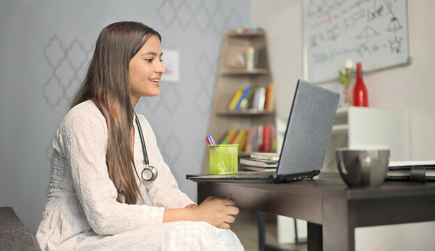 Indian Asian teen expert nurse lady use laptop look screen talk speak distant patient video call young adult gen z happy girl female doc staff do online health care work help home office clinic job