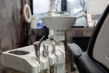 Dental handpieces in foreground with chair and window in background