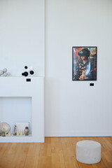 Minimalistic living room with white walls showcasing artwork and decorative items on shelves, illuminated by natural indoor lighting