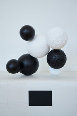 White and black spherical objects arranged in a balanced manner on a smooth surface creating an intriguing visual effect
