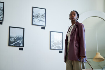 Portrait of an African American woman wearing a blazer and carrying a handbag while observing art...
