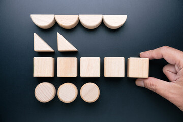 Hand arranging geometric wooden toys so that each shape is in a row, category concept