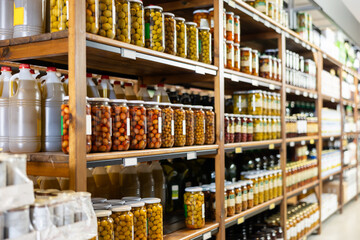 Marinated whole unpitted green olives in glass jars offered for sale on shelf rack in store....