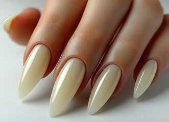 Close-up of Elegant Cream-Colored Manicured Nails with Glossy Finish and Pointed Shape on Female Hand
