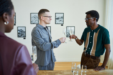 Group of people in a modern art gallery, toasting with champagne after watching paintings