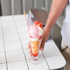 a hand hold a glass of strawberry parfait