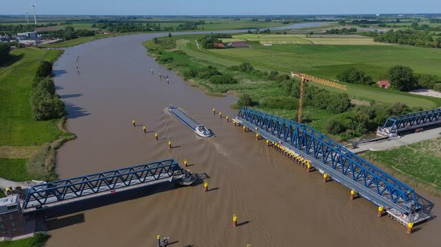 Aerial view of the Friesenbr&uuml;cke in open position as a cargo ship passes through. The swing-lift railway bridge spans the Ems River near Weener, showcasing modern German infrastructure in action.