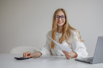 Young woman calculating finances at a modern desk while smiling during work hours at home