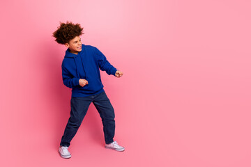 Happy young boy in stylish blue hoodie posing against pink background, showcasing youthful energy and casual fashion