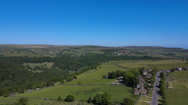 scenic aerial drone shot of slack bottom road near heptonstall showing houses along the road and trees in the hebden beck valley