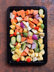 chopped mixed vegetables in a baking tray, preparing healthy meal ready for roasting