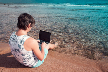 freelancer with a laptop works on a beach