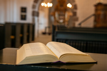 An open holy book rests at the front, gazing out over the church, where the chandelier glimmers above the nave